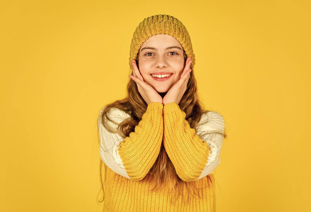 cheerful child wear hat and favorite sweater. childhood happiness. teen girl yellow background. little girl in knitwear. kid beauty and fashion. get warm in winter season. cold weather forecast - Fotografie, Obrázek