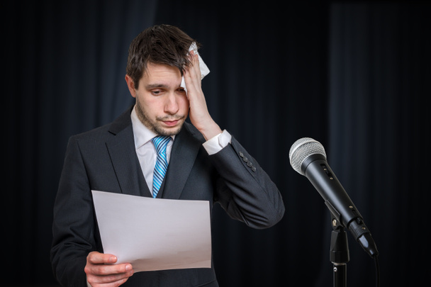 Sweating nervous speaker is afraid of public speech. Microphone in front. - Fotografie, Obrázek