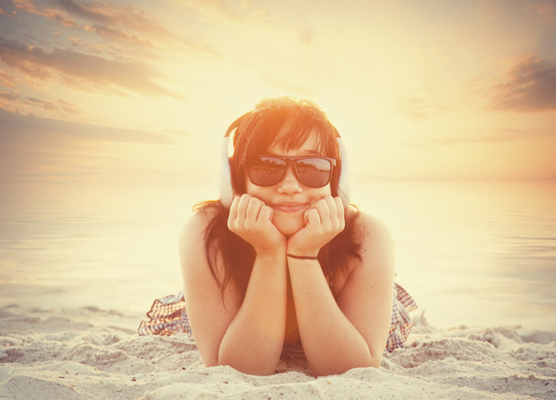 Brunette girl in sunglasses and headphones - Fotó, kép