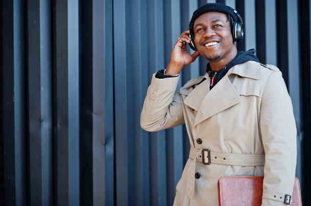 African american man with headphones, wear on hat and coat listening music on steel background. - Photo, Image