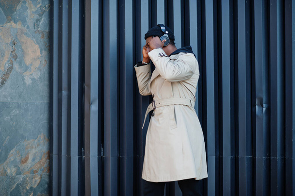 African american man with headphones, wear on hat and coat listening music on steel background. - Fotó, kép