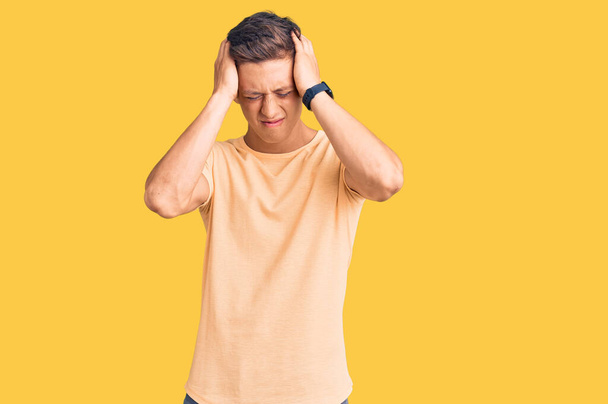 Junge gutaussehende Mann in legerer Kleidung leiden unter Kopfschmerzen verzweifelt und gestresst, weil Schmerzen und Migräne. Hände auf den Kopf.  - Foto, Bild