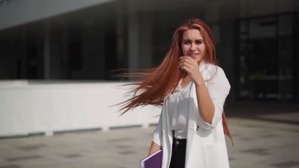 Beautiful confident business woman with red hair in fashion clothes smiles and rejoices. Lady enjoying successful corporate career. Female entrepreneur spinning with happiness downtown. Slow motion. - Footage, Video