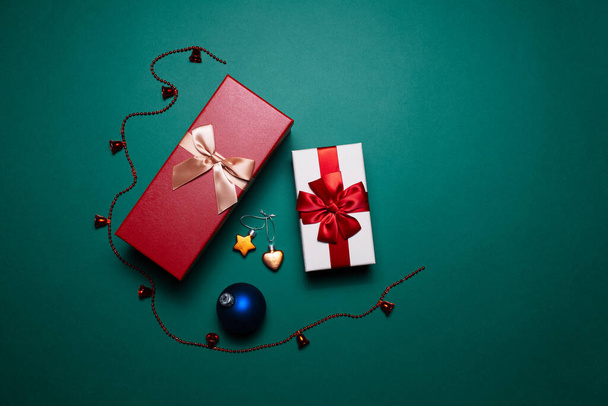 Christmas concept. Two red and white gift boxes with bows and decorations on background of green color. - Fotó, kép