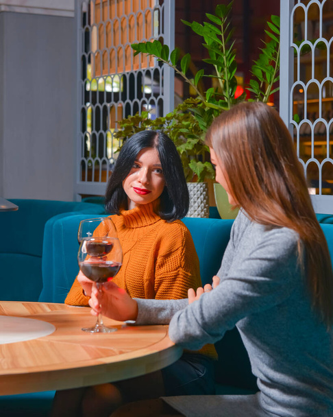 Two pretty cheerful women with glasses of wine in a restaurant. Leisure time, still life, eating out concept. - 写真・画像