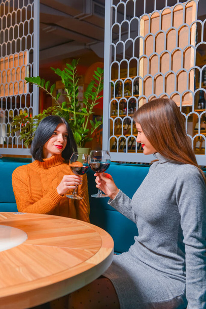 Two pretty cheerful women with glasses of wine in a restaurant. Leisure time, still life, eating out concept. - Фото, изображение