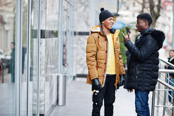 Dois amigos africanos do sexo masculino conversando juntos, usar em casacos em tempo frio. - Foto, Imagem