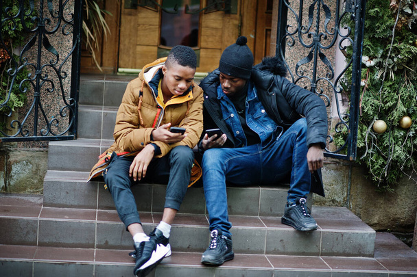 Two african male friends sitting and looking on phone together. - Фото, зображення