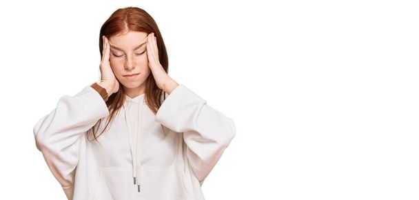 Młoda kobieta czytająca głowę w luźnej bluzie cierpiąca na ból głowy zdesperowana i zestresowana, ponieważ ból i migrena. ręce na głowę.  - Zdjęcie, obraz