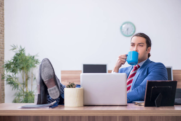 Young male employee drinking coffee during break - Foto, afbeelding