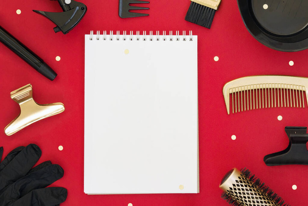 Hairdressing tools on a red background. Holiday template with an empty Notepad and space for text in the center. Hair salon accessories in gold and black. - Photo, Image