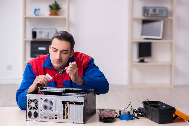 Молодий чоловік ремонтує комп'ютер
 - Фото, зображення