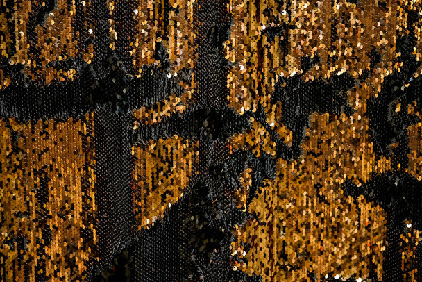 Reversible iridescent sequin fabric. Black and gold abstract glitter background. Festive double sided chameleon textile - Photo, Image