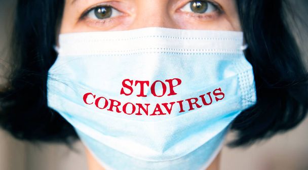 Woman wearing medical protective surgical face mask with text Stop coronavirus. Concept of protection against Covid-19, coronavirus outbreak campaign. - Foto, Imagen