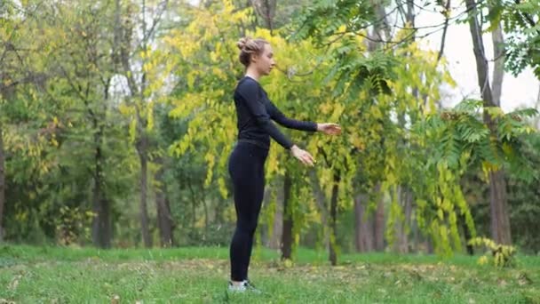 jonge vrouw oefent yoga in een stadspark op het gras - Video