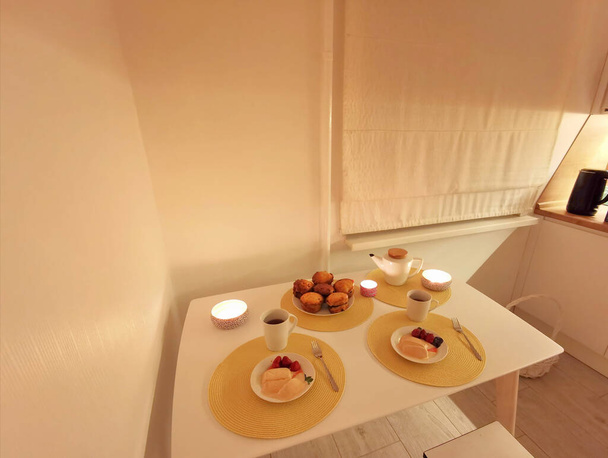キャンドルライトによる白いキッチンでロマンチックなディナー. - 写真・画像