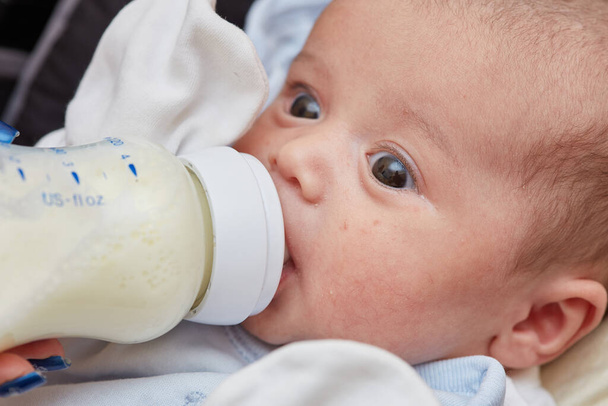 Gros plan sur un nouveau-né de 2 mois. Il y a de la nourriture pour bébé, du lait d'une bouteille. petite profondeur de mise au point. focus sélectif. - Photo, image