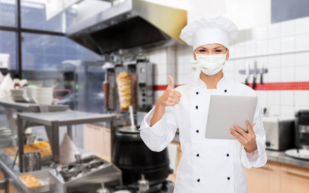 female chef in mask with tablet pc at kitchen - Foto, Imagem
