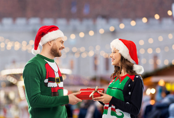 happy couple in christmas sweaters with gift box - Foto, Bild