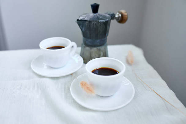 Dos tazas de café y cafetera italiana sobre la mesa en casa concepto de rituales de desayuno por la mañana, fondo de comida estilo de vida. - Foto, Imagen