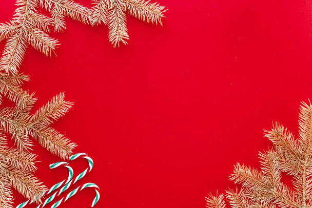 Roter Weihnachts- oder Neujahrshintergrund, einfache Komposition aus Tannenzweigen und Weihnachtsspielzeug, Flatlay, leerer Raum für Grußtext - Foto, Bild
