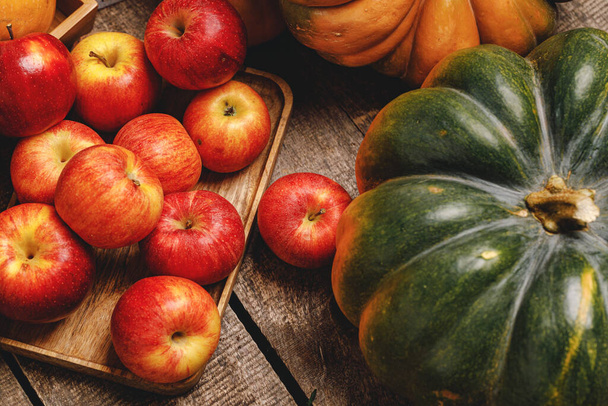 Pumpkins and red apples on wooden background - Photo, Image