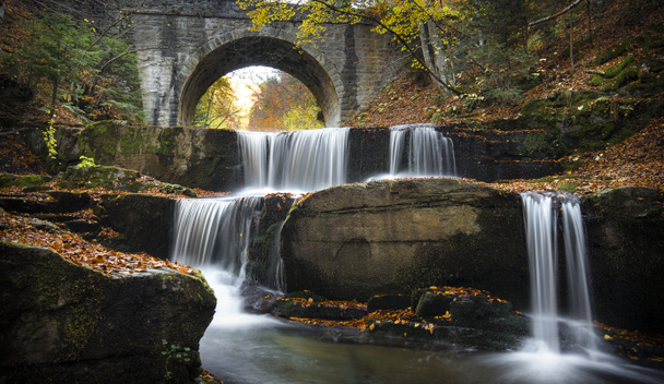 Autumn waterfalls near Sitovo, Plovdiv, Bulgaria. Beautiful cascades of water with fallen yellow leaves under the bridge. Sitovski waterfall - Photo, Image
