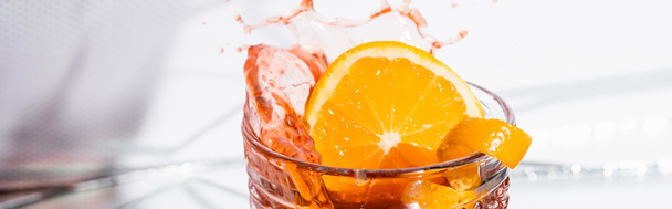 skórka pomarańczy w szkle z rozbryzganym koktajlem alkoholowym na białym, baner - Zdjęcie, obraz