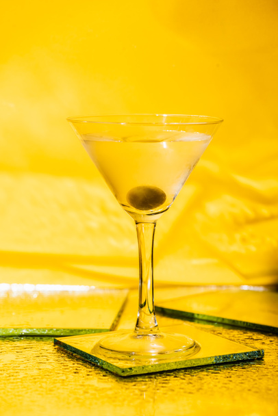 green olive in glass with martini on yellow  - Photo, Image