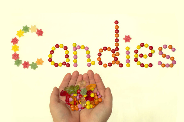 Een woord snoepjes bekleed met kleurrijke snoepjes op een lichte achtergrond - Foto, afbeelding