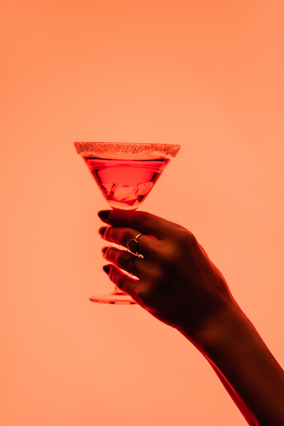partial view of young woman holding margarita cocktail with ice cubes on orange - 写真・画像