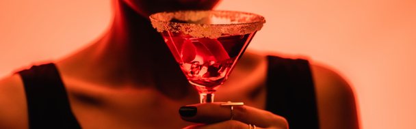 margarita cocktail with ice cubes and salt in hand of woman on blurred orange background, banner - Fotografie, Obrázek