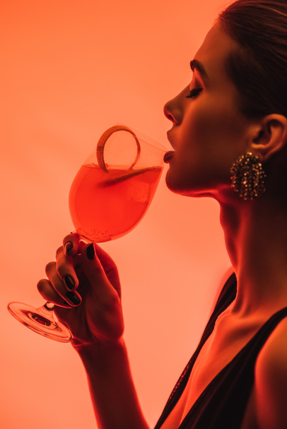 profilja nő gazdaság üveg vegyes koktél és narancshéj rózsaszín  - Fotó, kép