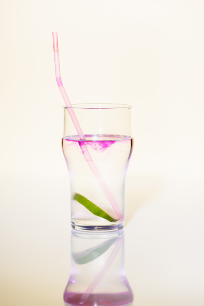 bicchiere con lime in bevanda alcolica con sciroppo viola su bianco - Foto, immagini