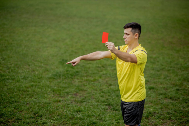 Angry football referee showing a red card and pointing with his hand on penalty. - Φωτογραφία, εικόνα