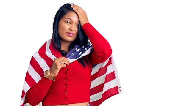 Birleşik Devletler bayrağını tutan uzun saçlı İspanyol kadın. Eli kanlı, şaşırmış ve kızgın yüzüyle stresli ve hayal kırıklığına uğramış.  - Fotoğraf, Görsel