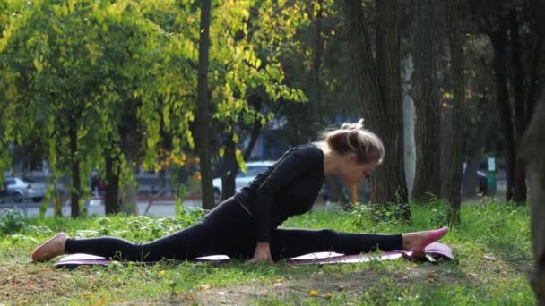 Young woman practices yoga in a city park On the grass - Footage, Video