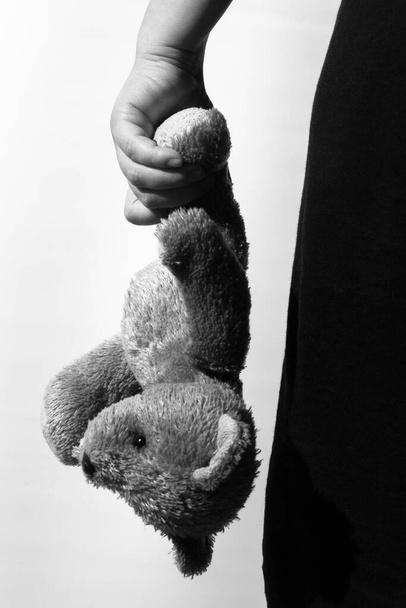 Black and white photo of a girl holding a teddy bear, theme of social problems - Foto, Imagen