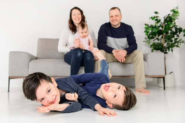 Agitated young boys family at home with the parent sit on sofa - Fotografie, Obrázek