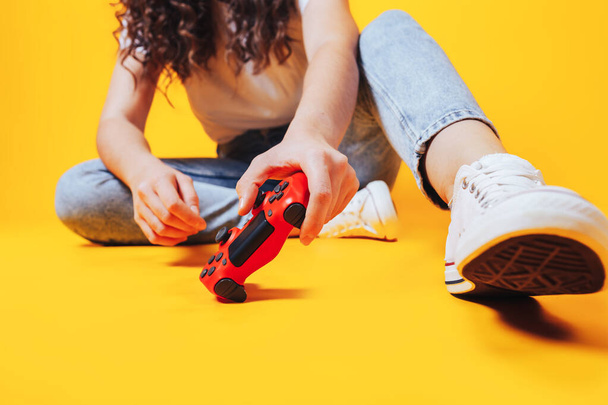 Woman holding gamepad in her hands in against of a yellow background. Promotion of women's esports. Advertising for the promotion of esports equipment. Place for text. - Photo, Image