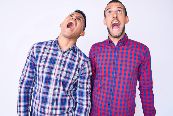 Young gay couple of two men wearing casual clothes angry and mad screaming frustrated and furious, shouting with anger. rage and aggressive concept.  - Fotoğraf, Görsel