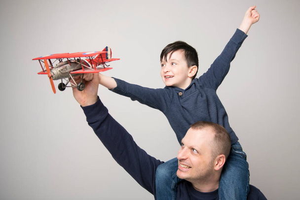 Cute boy and her handsome father play with plane and smiling while at home - Zdjęcie, obraz