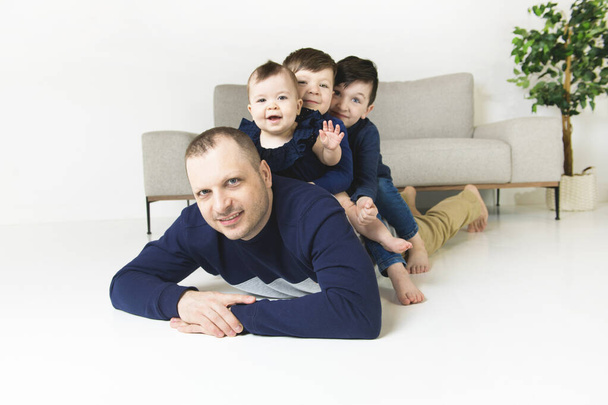 Cute boys and baby with father looking at camera and smiling while at home - Fotografie, Obrázek