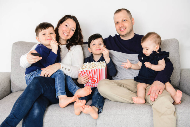Family Sitting On Sofa Watching movie Together with popcorn - Foto, afbeelding