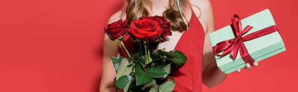 cropped view of woman holding roses and gift box on red, banner - Fotoğraf, Görsel