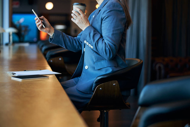 Elegant businesswoman drinking coffee and using smartphone - Photo, image