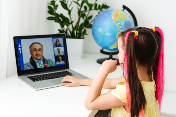 Coole Online-Schule. Kind lernt online zu Hause mit Laptop. Fröhliche junge Mädchen mit Laptop-Computer lernen durch Online-E-Learning-System. Distanz oder Fernstudium - Foto, Bild