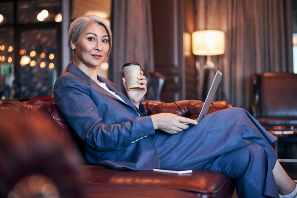 Charming woman drinking coffee and using laptop at business center - Fotoğraf, Görsel