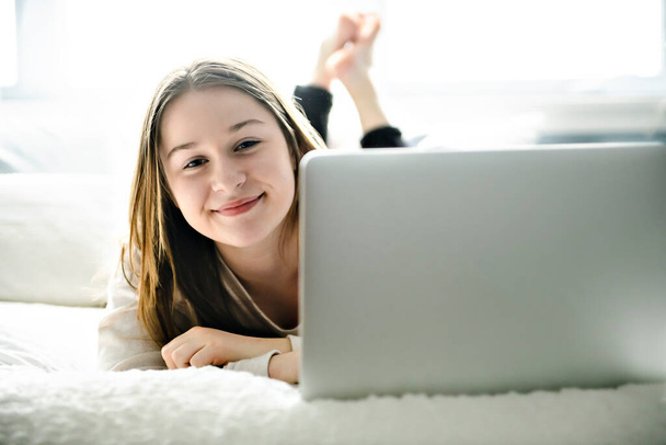 A Young smiling teen girl on bed with laptop - Foto, Imagem