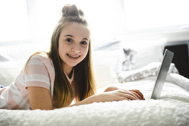 A Young smiling teen girl on bed with laptop - Fotoğraf, Görsel